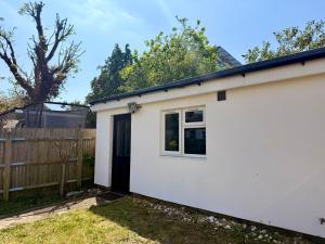 a white house with a door and a fence at Leatherhead Studios by WorkStay in Leatherhead