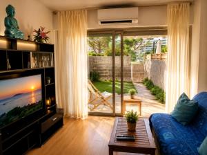 a living room with a blue couch and a tv at Studio Rez de jardin Marina baie des Anges in Villeneuve-Loubet