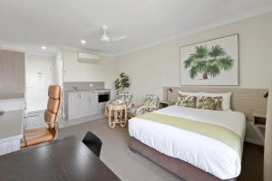 a bedroom with a bed and a table and a kitchen at Beachside Boutique Motel Mackay in Mackay
