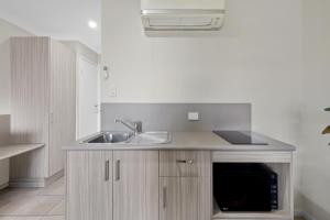 a kitchen with a sink and a microwave at Beachside Boutique Motel Mackay in Mackay
