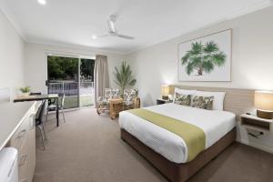a hotel room with a bed and a desk and a kitchen at Beachside Boutique Motel Mackay in Mackay