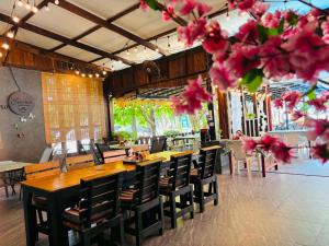 a restaurant with wooden tables and chairs and pink flowers at Emma in Ban Pak Khlong Phe