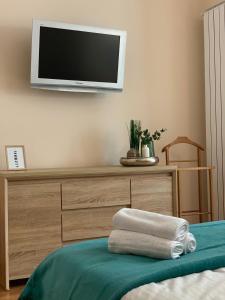 Ein Fernseher an der Wand über einer Kommode mit Handtüchern. in der Unterkunft Super Central Chic Studio-free coffee, self check in & check out in Oradea