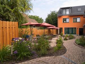 a garden with tables and umbrellas in front of a house at Ferienhof Radlerslust in Großkoschen