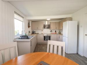 a kitchen with a table and a white refrigerator at Maes Y Coed in Pwllheli