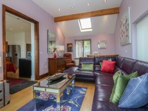 a living room with a leather couch and a table at Gwylan Uchaf in Y Felinheli
