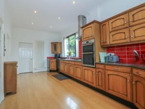 a large kitchen with wooden cabinets and red tiles at Gwylan Uchaf in Y Felinheli