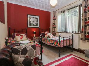 two beds in a room with red walls at Gwylan Uchaf in Y Felinheli