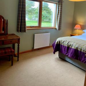a bedroom with a bed and a desk and a window at Brackenbrae Holiday Cottage in Acharacle