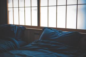 an unmade bed in a room with a window at Nuu Takedamise, the Villa in Kami-yuge