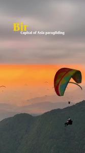 a person is flying a kite in the sky at Sunshine Cottages in Bīr
