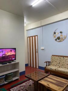 a living room with a tv and a couch and a table at Pine Forest Home stay with City View in Shillong