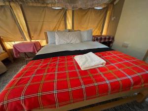 a red bed in a tent with two towels on it at Ntito Mara lodge in Maasai Mara National Reserve +34 photos