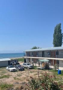 a building with cars parked in front of the ocean at Prestizh Guest House in Tamchy