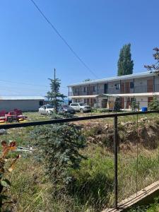 a fence in front of a building with cars parked at Prestizh Guest House in Tamchy +2 photos