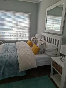 a bedroom with a bed with yellow pillows and a mirror at 7onthebeach unit 3 in Jeffreys Bay