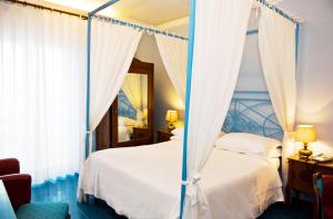 a bedroom with a canopy bed with a mirror at Hotel Palladio in Giardini Naxos
