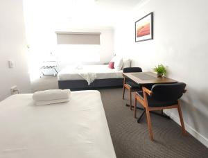 a room with two beds and a desk and a bed at Gunnedah Lodge Motel in Gunnedah