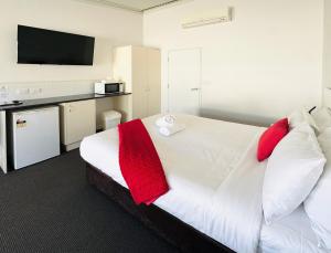 a bedroom with a large white bed with red pillows at Gunnedah Lodge Motel in Gunnedah