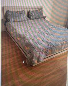 an unmade bed in a bedroom with a wooden floor at sadam nahwi in Dukem