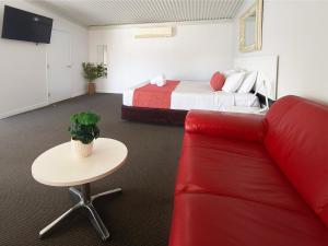 a hotel room with a bed and a red couch at Gunnedah Lodge Motel in Gunnedah