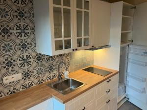 a kitchen with white cabinets and a sink at The Tiny House in Nieuwpoort