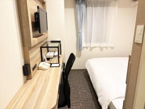 a hotel room with a bed and a desk with a phone at Smile Hotel Kitaasaka in Asaka