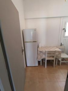 a kitchen with a white refrigerator and a table at Klimatsias Beach Apartment in Pesádha