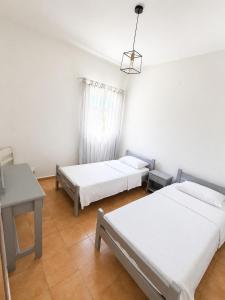 a room with two beds and a table and a window at Klimatsias Beach Apartment in Pesádha