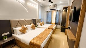 two beds in a hotel room with a television at Hotel City Palace in Varanasi