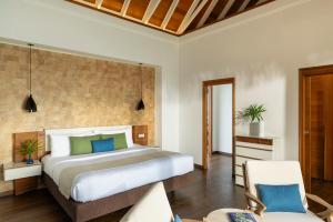 a bedroom with a large bed and a chair at Kandolhu Maldives in Mushimasgali