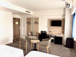 a hotel room with a living area with a table and chairs at Smile Hotel Kitaasaka in Asaka