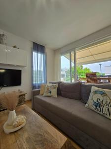 a living room with a couch and a large window at Apartman Oscar with pool access in Petrcane