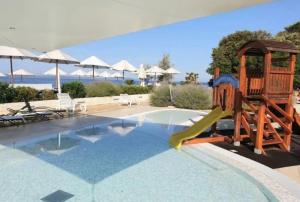 a pool with a slide and a playground at Apartman Oscar with pool access in Petrcane