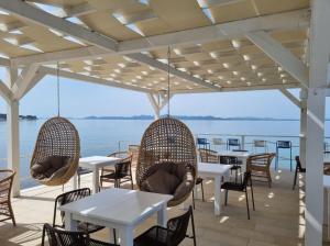 a patio with tables and chairs and a view of the water at Apartman Oscar with pool access in Petrcane