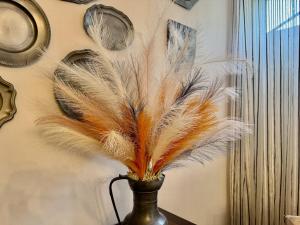 a vase filled with feathers on top of a table at Le Clos des Lys, Maison de Pays Raffinée Proche de la Mer in Saint-Georges-dʼOléron