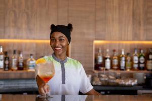 a woman is holding a drink in a bar at Kandolhu Maldives in Mushimasgali
