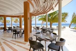 a restaurant on the beach with tables and chairs at Kandolhu Maldives in Mushimasgali