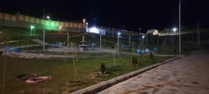 a park at night with a fountain in the grass at Bam Asia Five Star Hotel in Bāmīān
