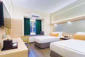 ein Hotelzimmer mit zwei Betten und einem Fernseher in der Unterkunft Microtel by Wyndham Tarlac in Tarlac City