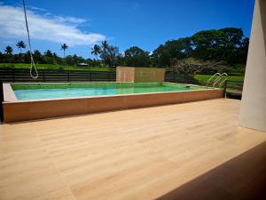a swimming pool with a wooden floor in front at villa 911 in Pacific Harbour