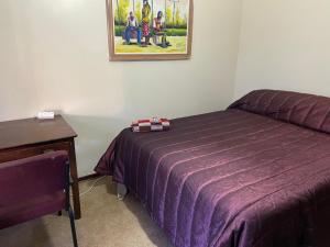 a bedroom with a purple bed next to a desk at Highway Haven in Stilfontein