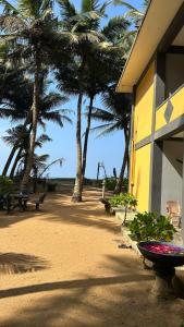 a beach with palm trees and a yellow building at Jasmin Garden in Kalutara