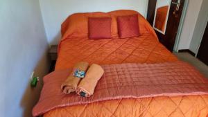a bedroom with two beds with orange sheets and red pillows at Highway Haven in Stilfontein