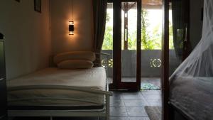 a bedroom with a bed and a door to a porch at Sumatra Orangutan Discovery Villa in Bukit Lawang