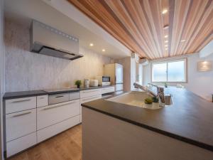 a kitchen with white cabinets and a wooden ceiling at マークヴィラ松本 in Matsumoto