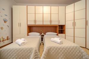 two beds in a room with white cabinets at Casa Lella in Novara