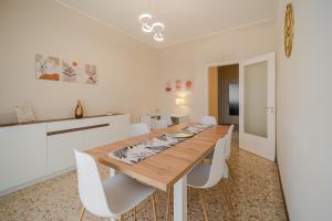 a dining room with a wooden table and white chairs at Casa Lella in Novara