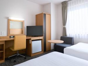 a hotel room with a bed and a desk with a television at Comfort Hotel Himeji in Himeji