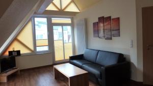 ein Wohnzimmer mit einem schwarzen Sofa und einem Tisch in der Unterkunft Sonneneck in Norderney